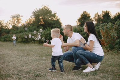 Family with cute little child. Father in a white shirt. People plays with bubbles.